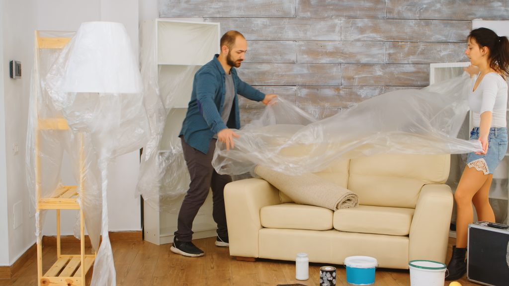 living space covered in painter’s tarp with other contractor materials and paint 
