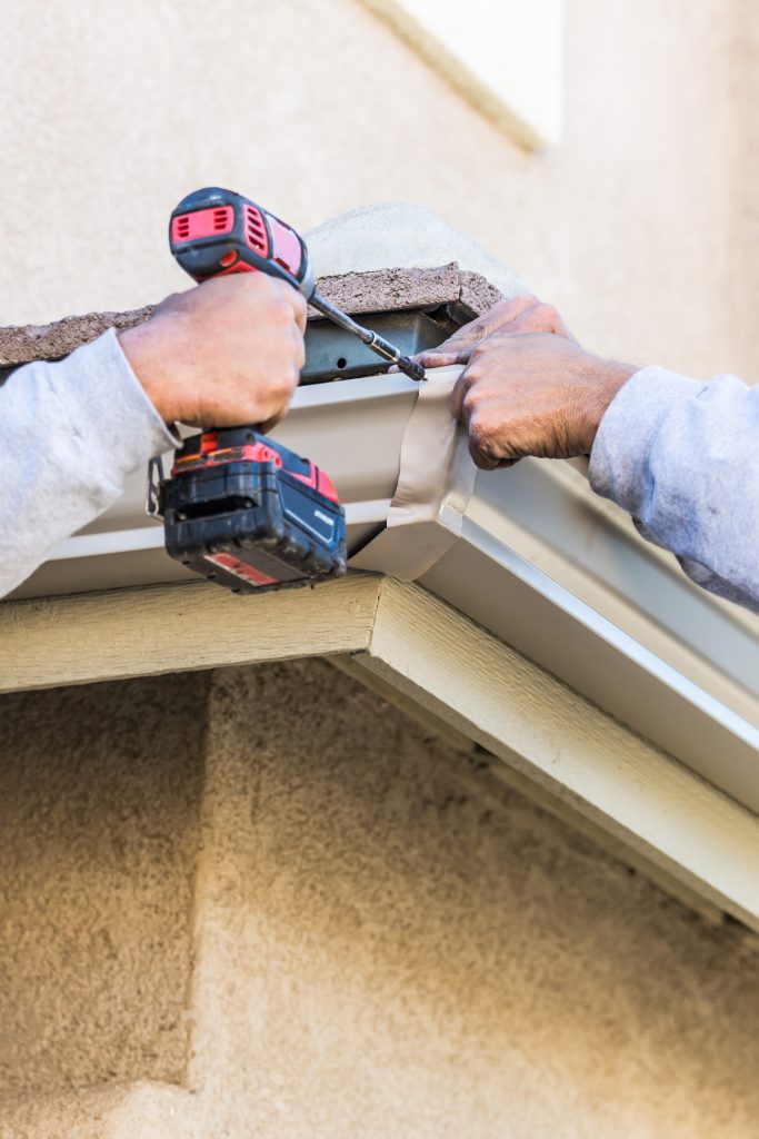 professional contractors installing a new gutter on a home